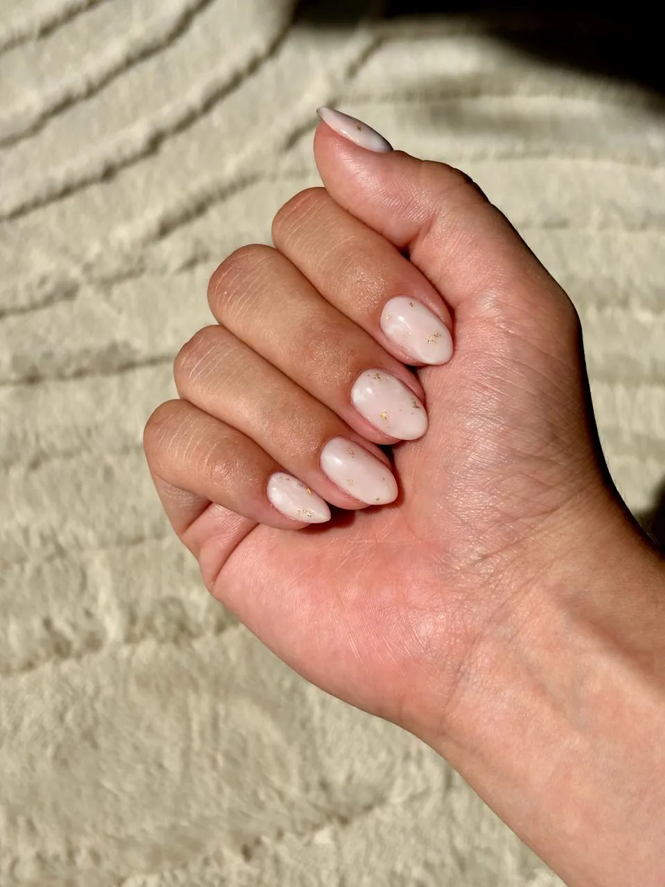 Unhas em gel finalizadas em tom claro com detalhes dourados
